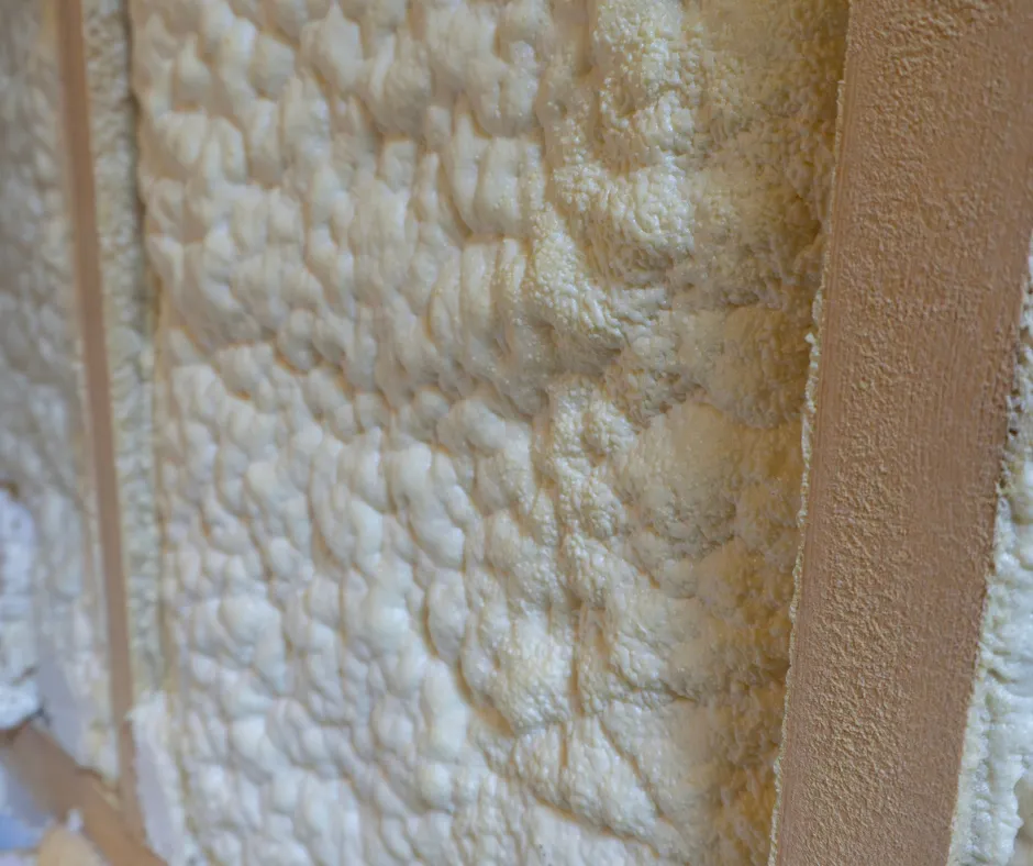 Close-up of closed-cell spray foam insulation applied in wall cavity between studs by Level Home Pros in Chesapeake VA